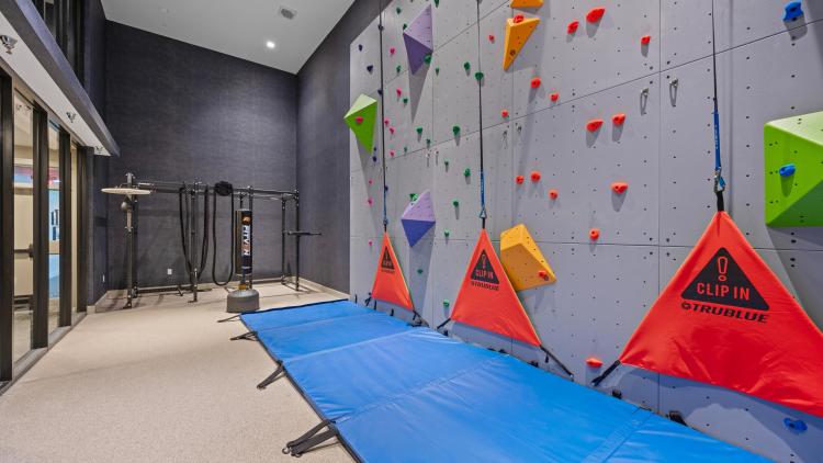 Indoor rock climbing wall with blue mat on floor underneath