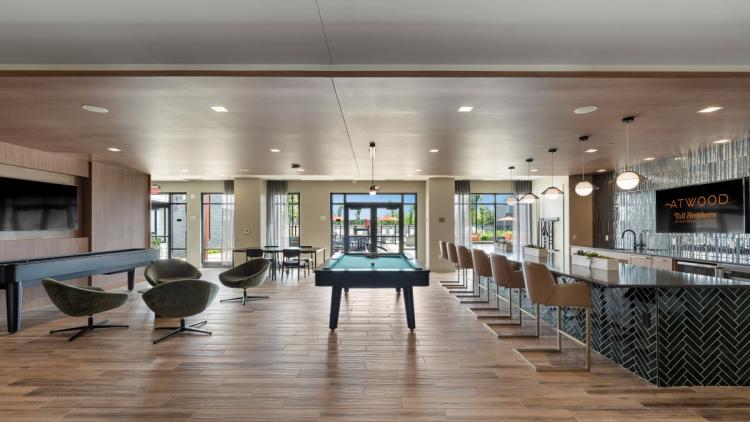 Large room with a bar on one side and seating and a pool table