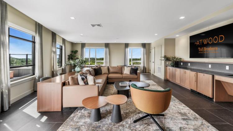 Room with a large leather couch and chairs facing a television on the wall