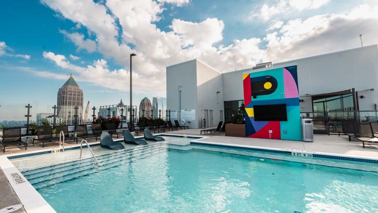 Outdoor pool with a TV hanging nearby