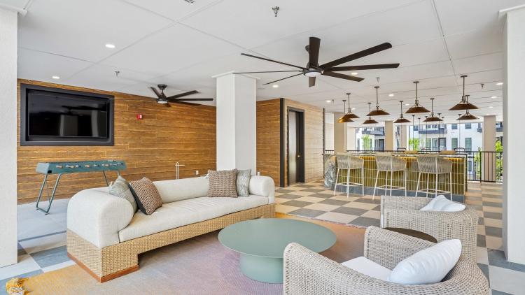 Outdoor covered space with couch, TV, and bar seating