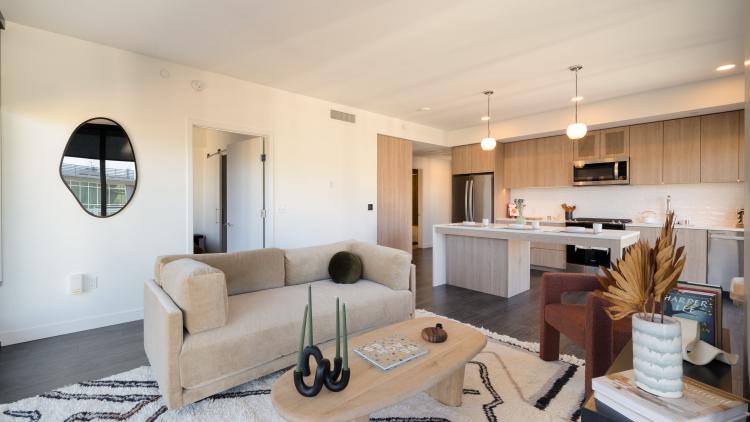 Living room with sofa and table, leading to kitchen