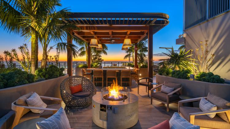 Outdoor space with fire pit, chairs and sofas around, and a covered cabana
