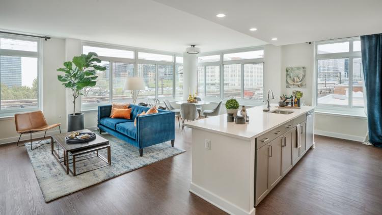 Apartment living room with kitchen island, sofa, chair, and a small dining table behind
