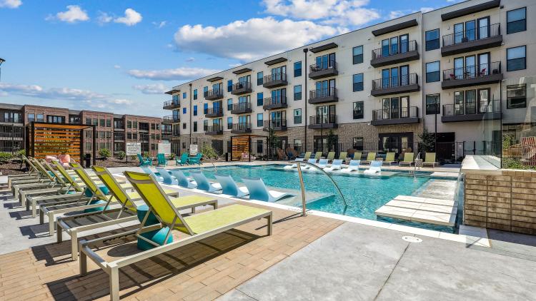 Pool with deck chairs and apartment building behind