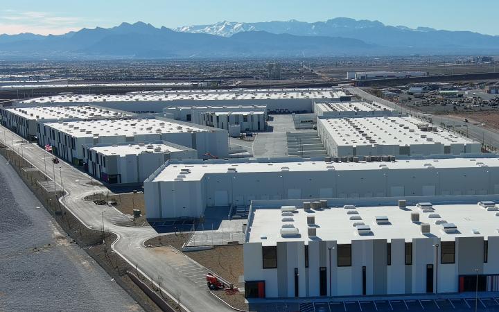 A collection of white warehouses with snowy mountains in the distance